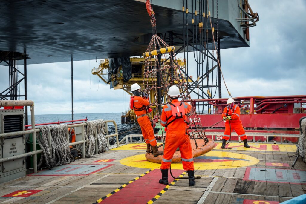 Offshore crew in red jumpsuits working on the deck of an oil platform.